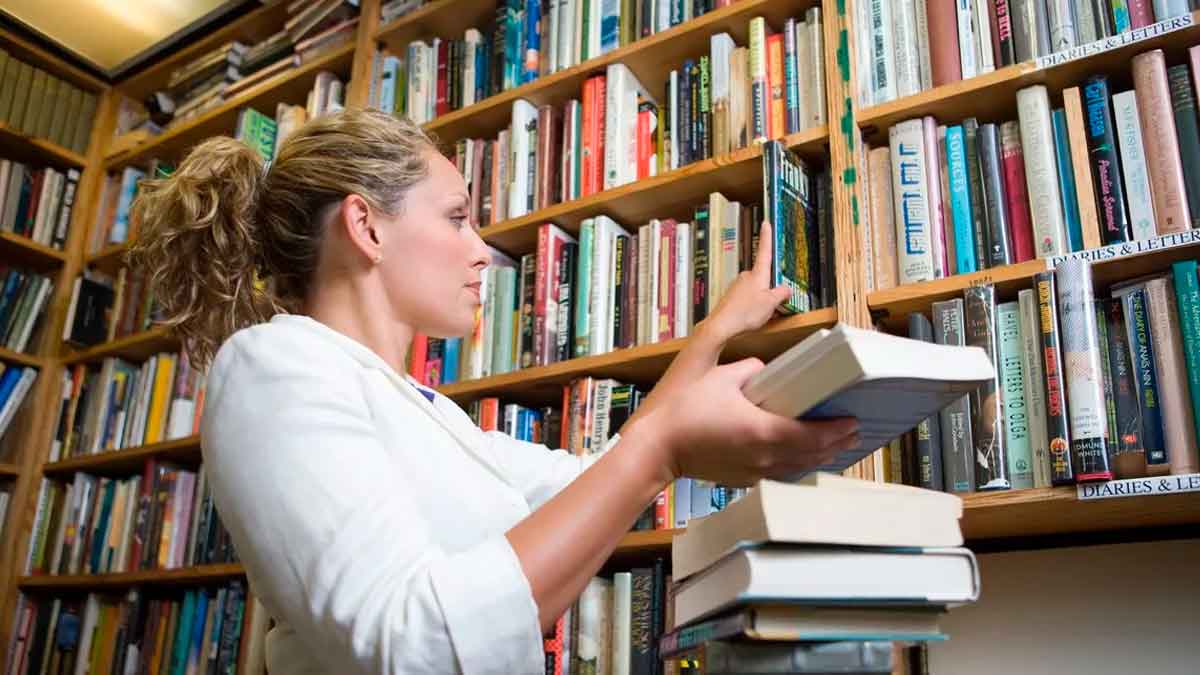 Bibliotecaria llevando libros a la estanteria