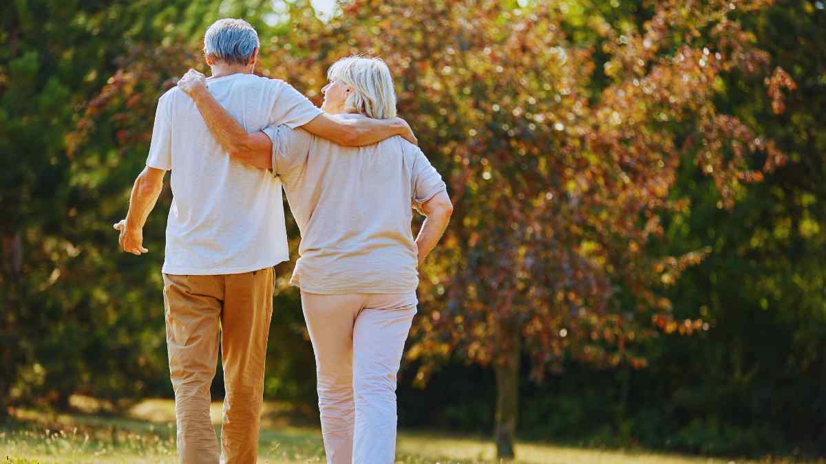 Pareja mayor caminando en un parque, ejemplo de envejecimiento saludable con actividad física diaria.