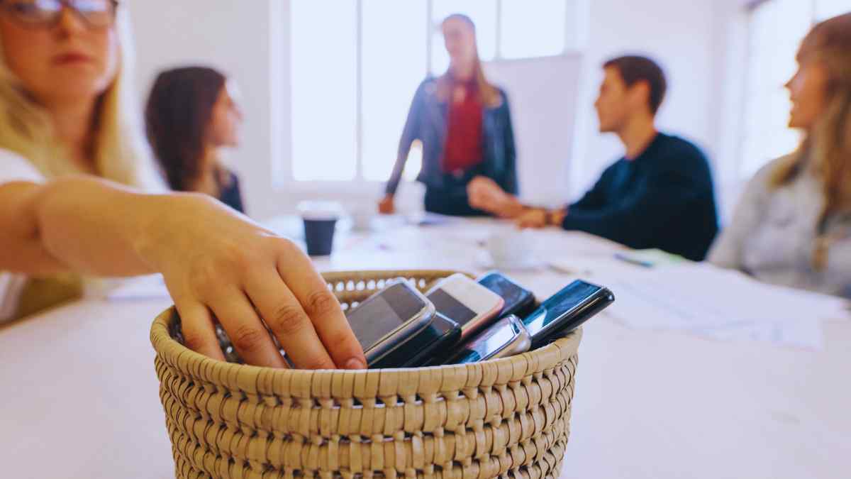 Trabajadores dejando sus móviles en una cesta, representando el derecho a la desconexión digital laboral en 2025