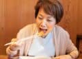 Mujer japonesa disfrutando de una comida saludable, representando la dieta antiinflamatoria japonesa para la longevidad y pérdida de peso.