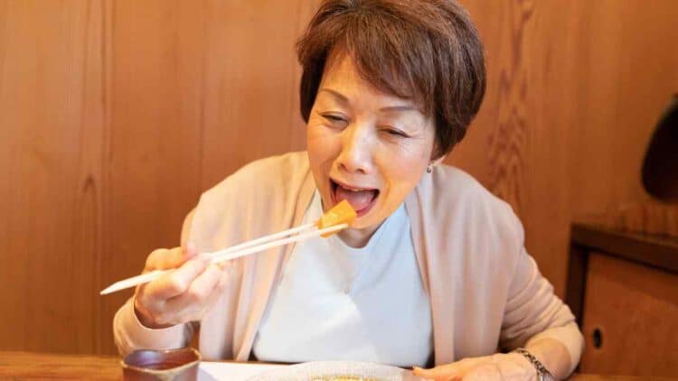 Mujer japonesa disfrutando de una comida saludable, representando la dieta antiinflamatoria japonesa para la longevidad y pérdida de peso.