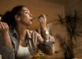 Mujer cenando en casa, destacando la importancia de la hora ideal para cenar y cuidar la salud