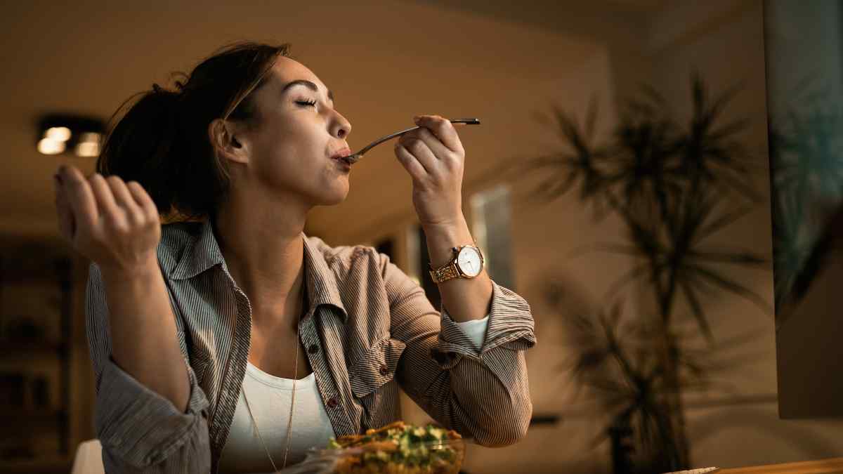 Mujer cenando en casa, destacando la importancia de la hora ideal para cenar y cuidar la salud