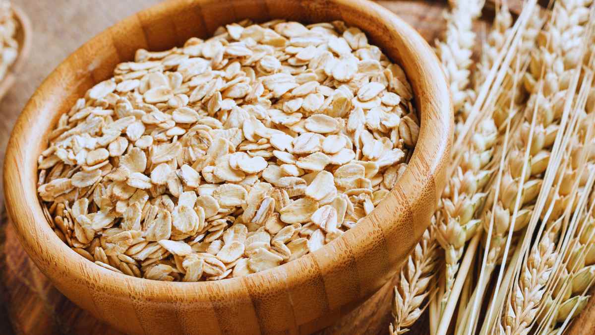 Tarro de avena acompañado de plantas de trigo.