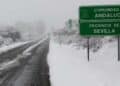 Carretera nevada en Sevilla, Andalucía, con un cartel señalizando la comunidad durante un temporal de lluvias y nieve.