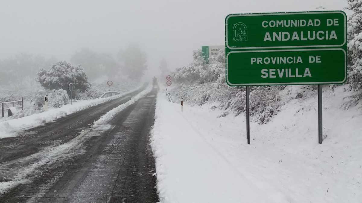 Carretera nevada en Sevilla, Andalucía, con un cartel señalizando la comunidad durante un temporal de lluvias y nieve.