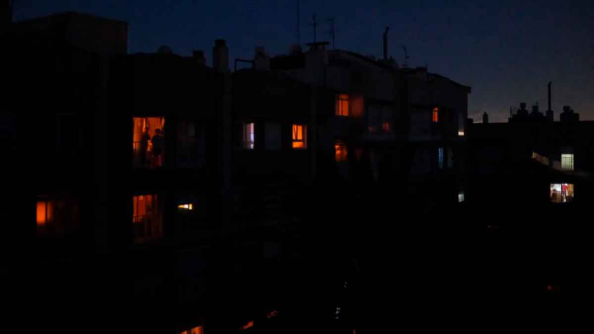 Personas en sus casas durante un apagón nocturno en España, con apenas unas luces encendidas entre la oscuridad