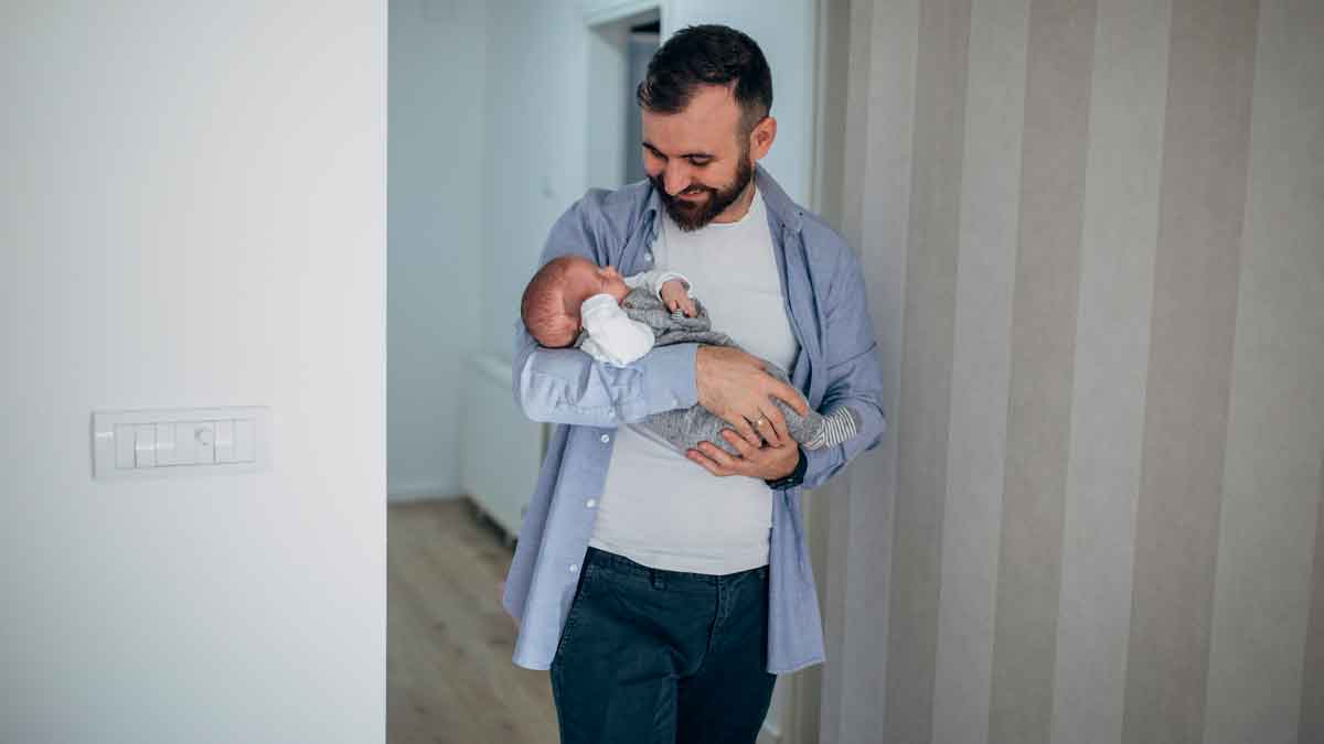 Padre con su bebé recién nacido en brazos durante la baja por paternidad, reflejo de la conciliación laboral y familiar