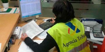 Funcionaria de la Agencia Tributaria revisando declaraciones fiscales en una oficina