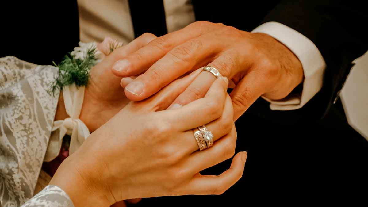 Manos de recién casados mostrando sus anillos de boda, ilustrando la importancia de declarar los regalos ante Hacienda