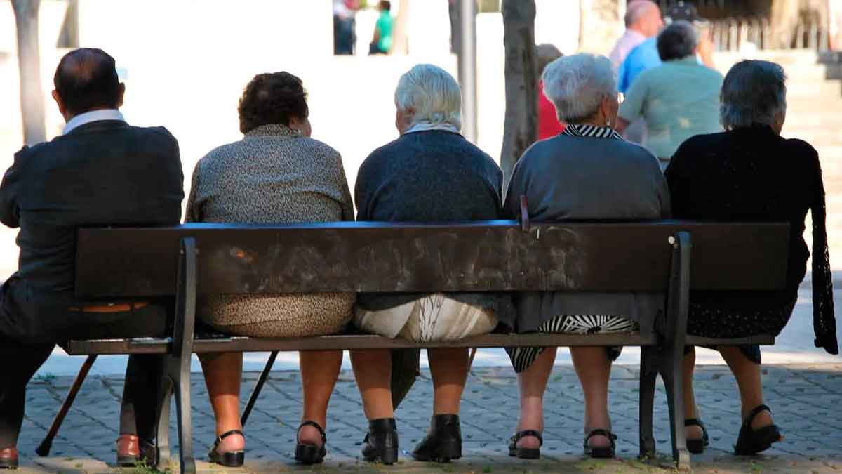 Grupo de pensionistas sentados en un banco esperando el complemento de abril de 2025