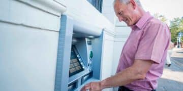 Hombre mayor retirando efectivo en un cajero automático, fechas de cobro de las pensiones en abril de 2025