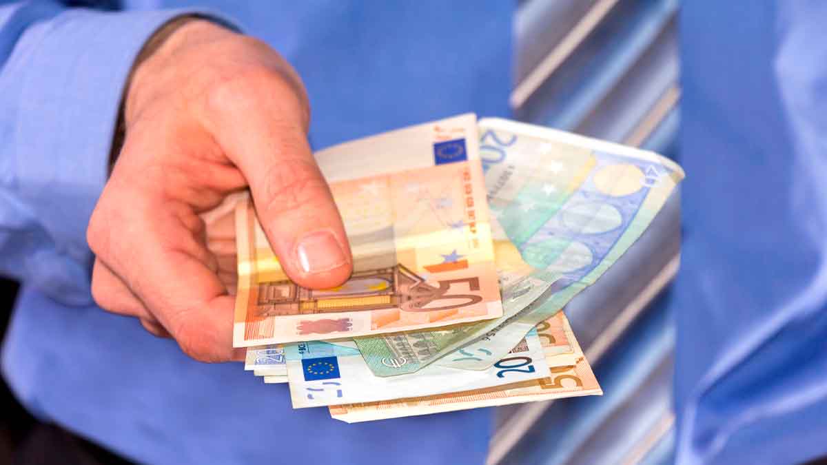 Persona con camisa y corbata sosteniendo billetes de euro, representando transferencias de dinero entre familiares