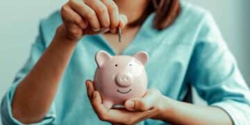 Mujer depositando una moneda en una hucha rosada para ilustrar el método 50/30/20 de ahorro según tu sueldo