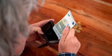Persona mayor revisando su cartera con un billete de 5 euros, simbolizando la compatibilidad de la pensión de viudedad y la jubilación