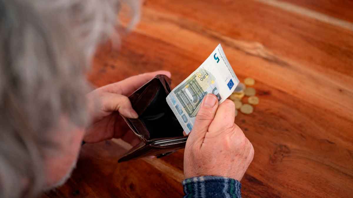 Persona mayor revisando su cartera con un billete de 5 euros, simbolizando la compatibilidad de la pensión de viudedad y la jubilación