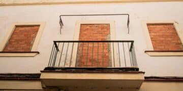 Fachada de vivienda vacía con ventanas tapiadas y balcón sin uso, ejemplo del coste anual de más de 3.000 €