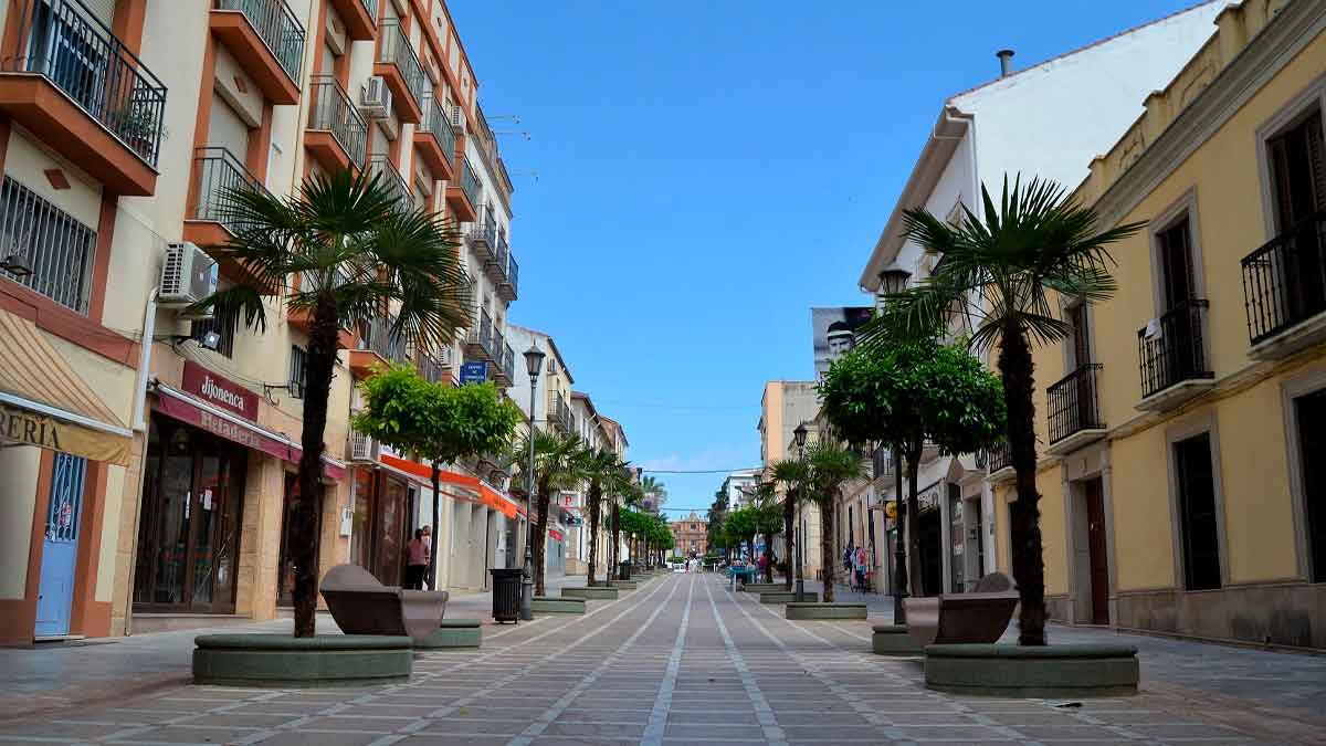 Calle principal de La Carolina (Jaén), el municipio más barato de Andalucía para comprar casa, con palmeras y comercios