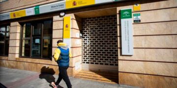 Persona caminando frente a una oficina de empleo del SEPE con la persiana parcialmente cerrada