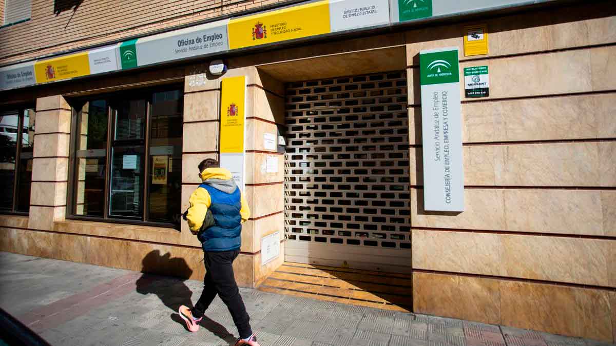 Persona caminando frente a una oficina de empleo del SEPE con la persiana parcialmente cerrada