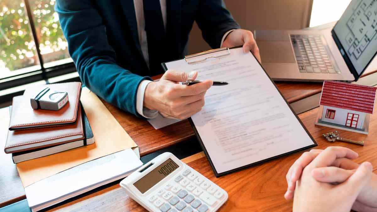 Asesor financiero muestra contrato de préstamo hipotecario y calculadora mientras explica TIN y TAE al cliente