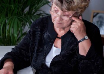 Mujer mayor con gafas revisando documentos de la Seguridad Social sobre su pensión de viudedad