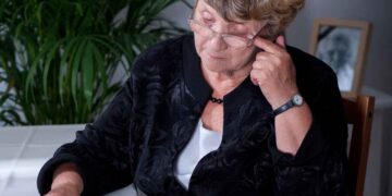 Mujer mayor con gafas revisando documentos de la Seguridad Social sobre su pensión de viudedad