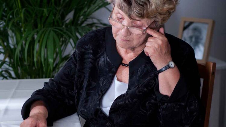 Mujer mayor con gafas revisando documentos de la Seguridad Social sobre su pensión de viudedad