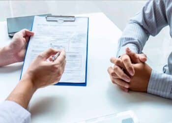 Trabajador del INSS muestra al solicitante un formulario de revisión de la pensión por incapacidad permanente.