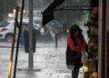 Mujer se resguarda de la lluvia intensa bajo un toldo en una calle de Andalucía