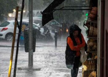 Mujer se resguarda de la lluvia intensa bajo un toldo en una calle de Andalucía