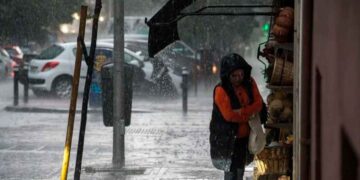 Mujer se resguarda de la lluvia intensa bajo un toldo en una calle de Andalucía