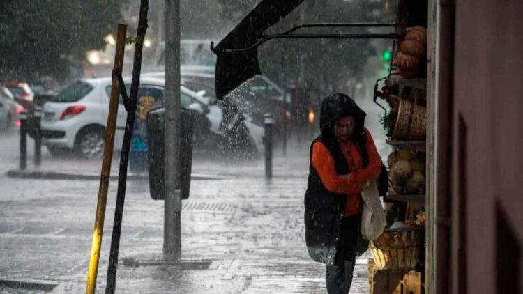 Mujer se resguarda de la lluvia intensa bajo un toldo en una calle de Andalucía