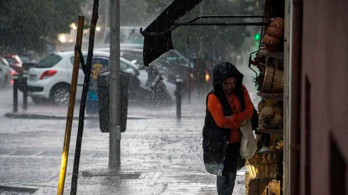 Mujer se resguarda de la lluvia intensa bajo un toldo en una calle de Andalucía