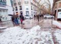 Acumulación de granizo en una calle céntrica andaluza tras la tormenta del 8 de mayo de 2025, con viandantes y charcos