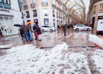 Acumulación de granizo en una calle céntrica andaluza tras la tormenta del 8 de mayo de 2025, con viandantes y charcos