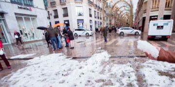 Acumulación de granizo en una calle céntrica andaluza tras la tormenta del 8 de mayo de 2025, con viandantes y charcos