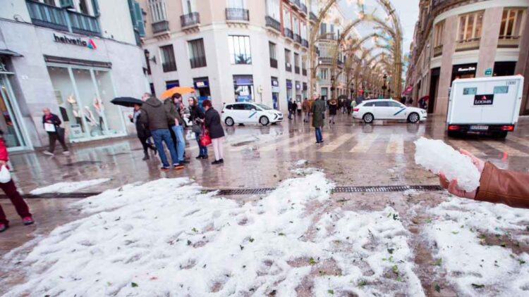 Acumulación de granizo en una calle céntrica andaluza tras la tormenta del 8 de mayo de 2025, con viandantes y charcos