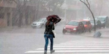 Mujer con paraguas cruza un paso de peatones durante un aguacero intenso en una calle andaluza, bajo aviso amarillo de la AEMET