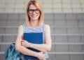 Estudiante universitaria sonriente con libros optando a una beca Santander de 12.000 euros