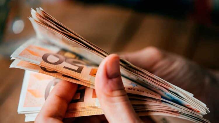 Persona contando billetes de 50 €, símbolo de compatibilizar salario parcial y subsidio del SEPE para un doble ingreso