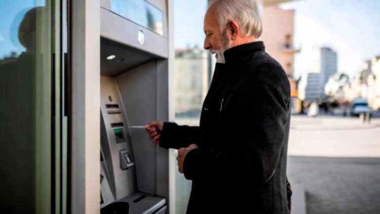 Hombre mayor retirando efectivo en un cajero automático tras recibir el adelanto del cobro de pensiones en mayo 2025