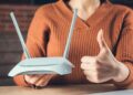 Mujer sostiene router y hace pulgar arriba, simbolizando la importancia de revisar contratos de telefonía e internet