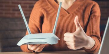 Mujer sostiene router y hace pulgar arriba, simbolizando la importancia de revisar contratos de telefonía e internet