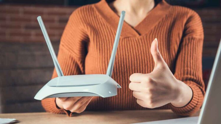 Mujer sostiene router y hace pulgar arriba, simbolizando la importancia de revisar contratos de telefonía e internet