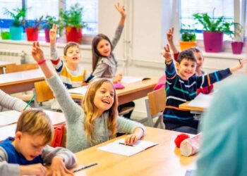 Alumnos de primaria levantan la mano en clase de idiomas, gasto educativo deducible en la renta de Andalucía