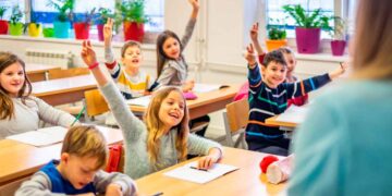 Alumnos de primaria levantan la mano en clase de idiomas, gasto educativo deducible en la renta de Andalucía