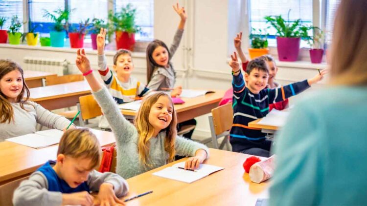 Alumnos de primaria levantan la mano en clase de idiomas, gasto educativo deducible en la renta de Andalucía