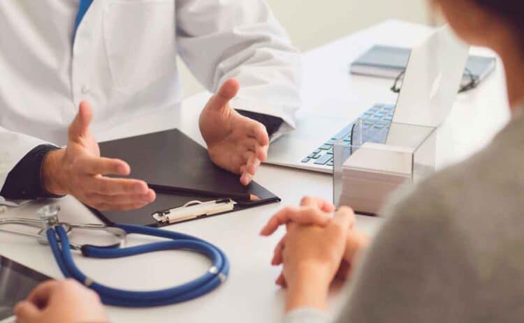 Médico explicando a un trabajador en baja médica cómo el despido afecta a su prestación por desempleo del SEPE