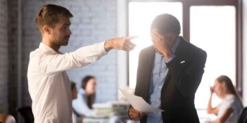 Jefe señalando la puerta a trabajador cabizbajo con carta en la mano, ejemplo de despido improcedente y posible reclamación de indemnización